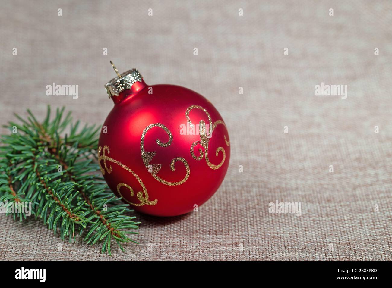 Boule d'arbre de Noël rouge et branche d'épinette sur tissu jute Banque D'Images