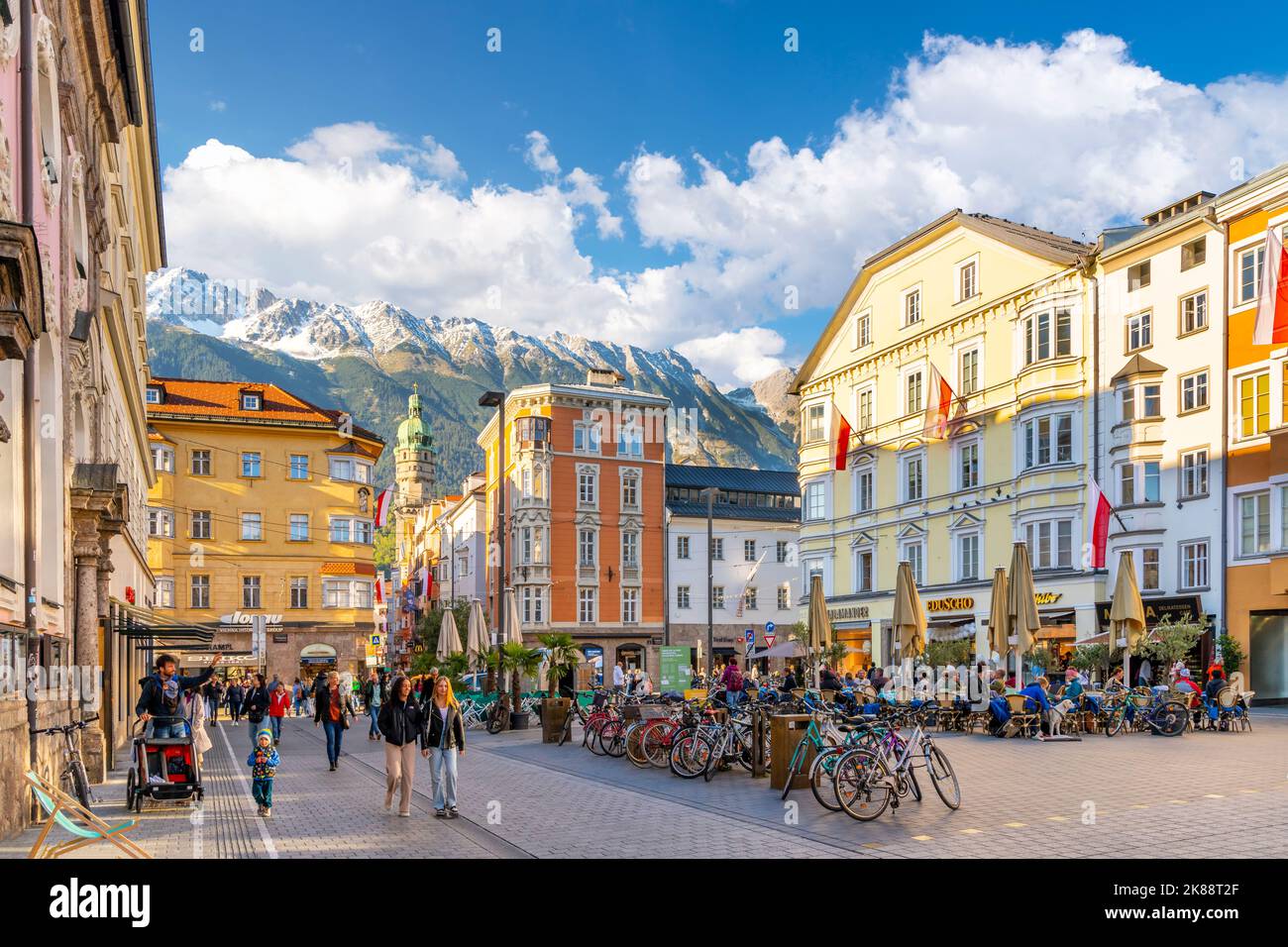 La place principale de la ville d'Innsbruck Autriche en tant que touristes apprécient les boutiques et les cafés avec l'église baroque de l'hôpital et les Alpes autrichiennes couvertes de neige Banque D'Images