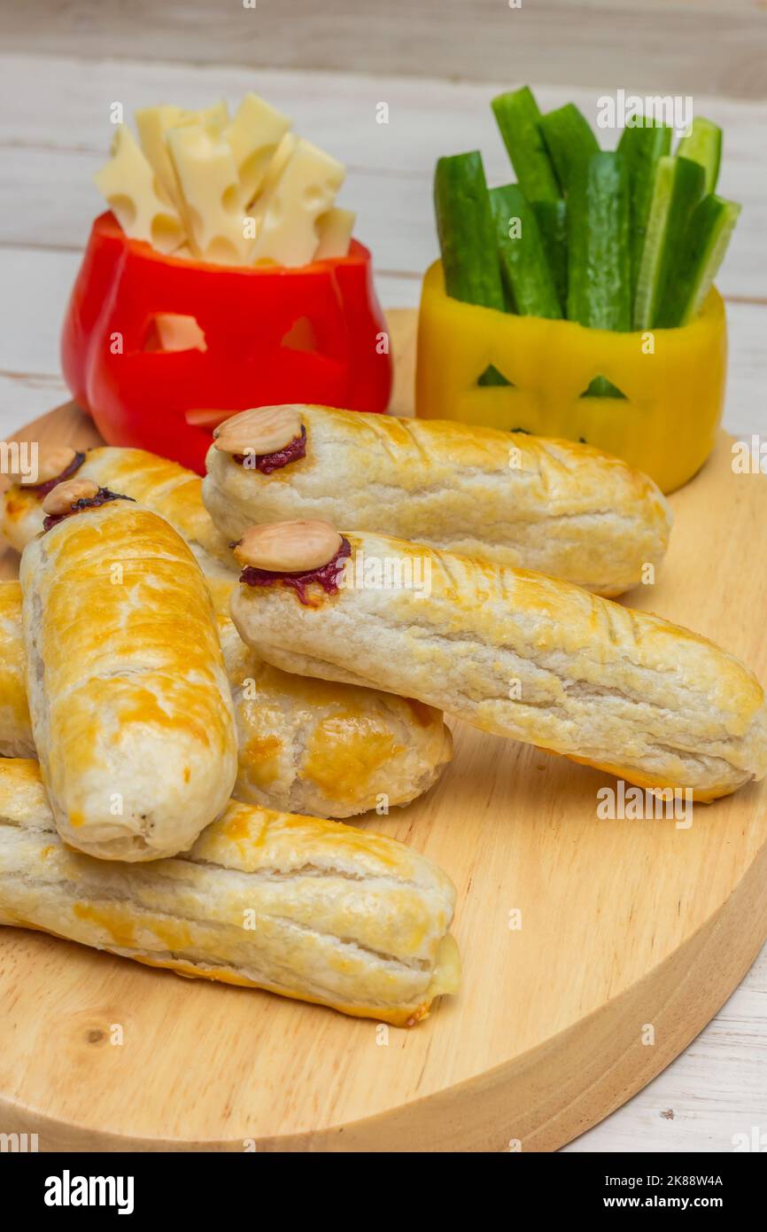 Nourriture d'Halloween avec visages effrayants dans des poivrons et avec des doigts avec des saucisses et du fromage Banque D'Images