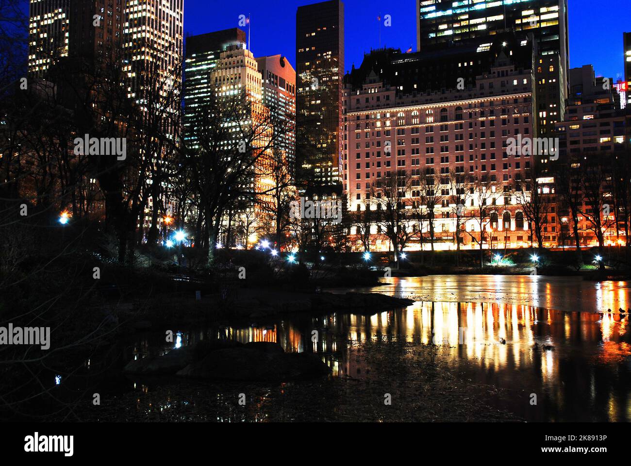 Les lumières de Manhattan et du Plaza Hotel se reflètent dans les eaux glacées de l'étang de Central Park, New York Banque D'Images