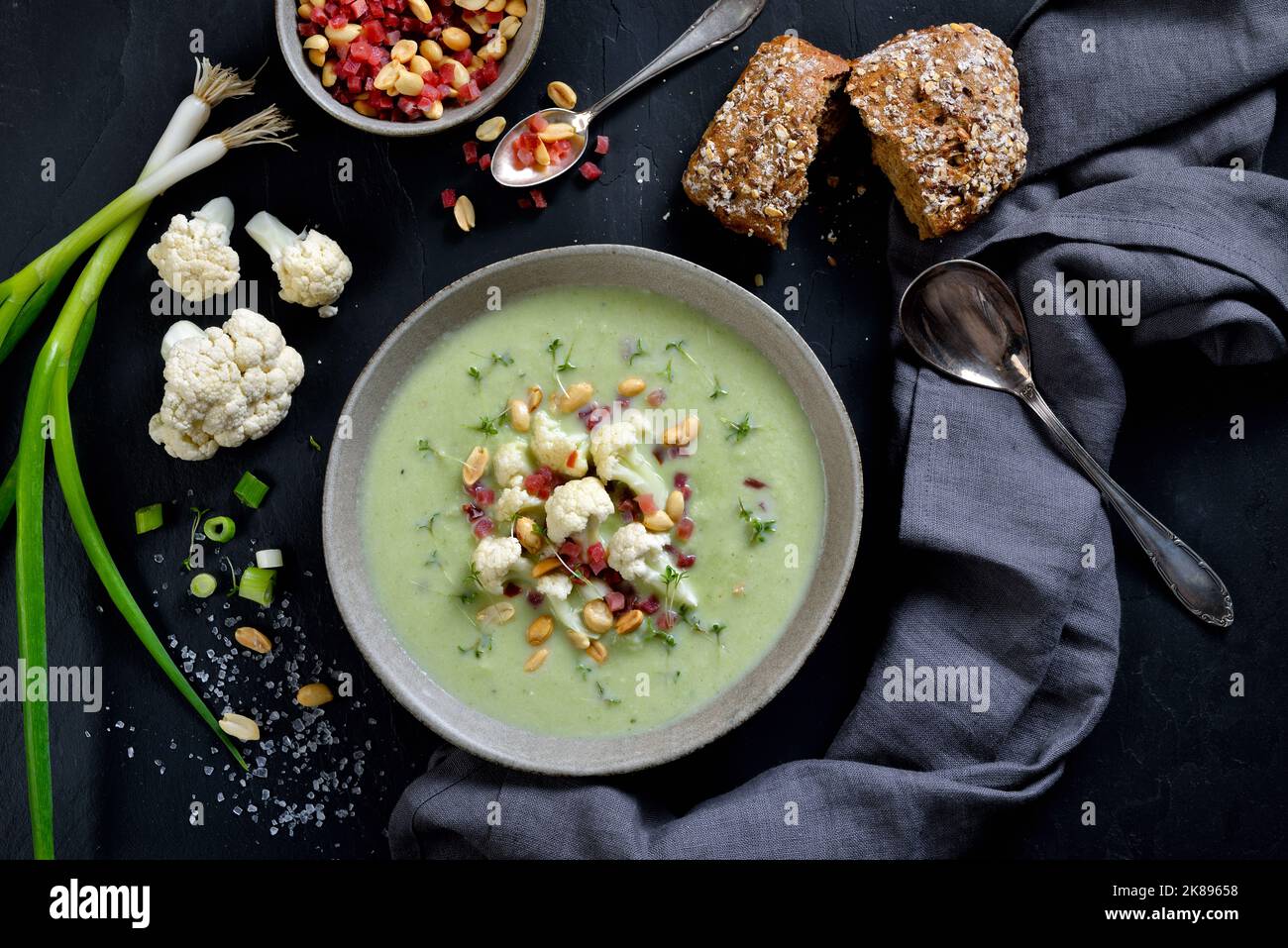 Soupe crémeuse de chou-fleur avec oignons de printemps, raifort, arachides et dés de jambon, servie avec un rouleau complet Banque D'Images Soupe crémeuse de chou-fleur avec oignons de printemps, raifort, arachides et dés de jambon, servie avec un rouleau complet Banque D'Images
