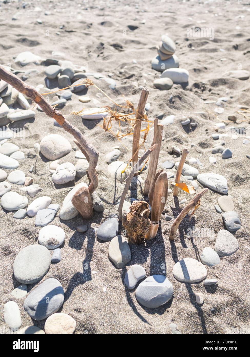 Pyramide construite avec des pierres et du bois flotté sur la plage de galets. Vacances en bord de mer. Explorer la nature dans l'enfance. Banque D'Images