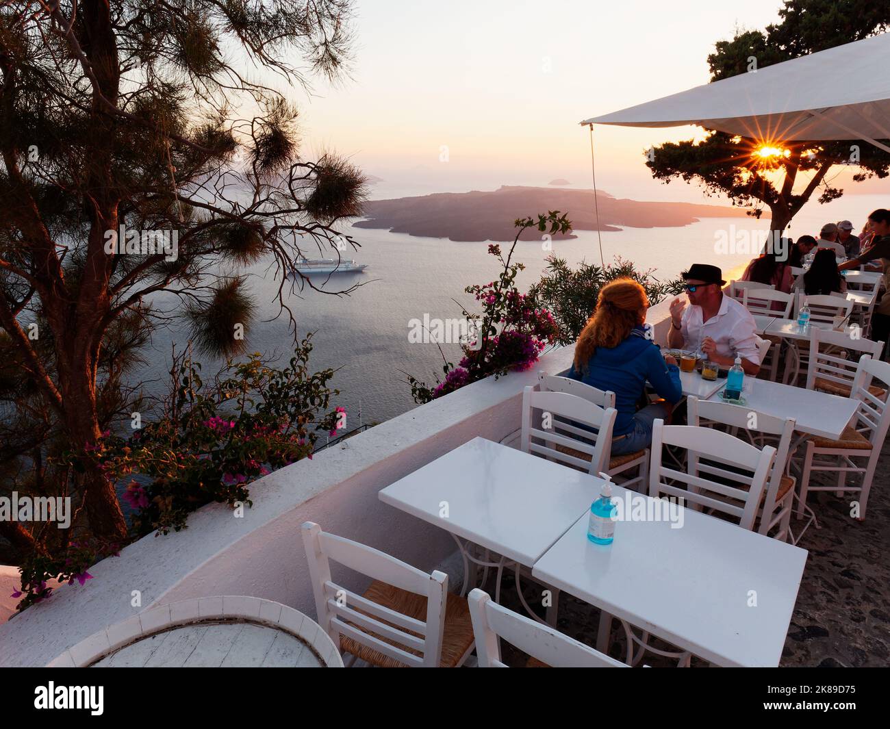 Restaurant avec vue sur la caldeira, dont un bateau de croisière au coucher du soleil à Santorin, une île grecque de la mer Égée. Banque D'Images