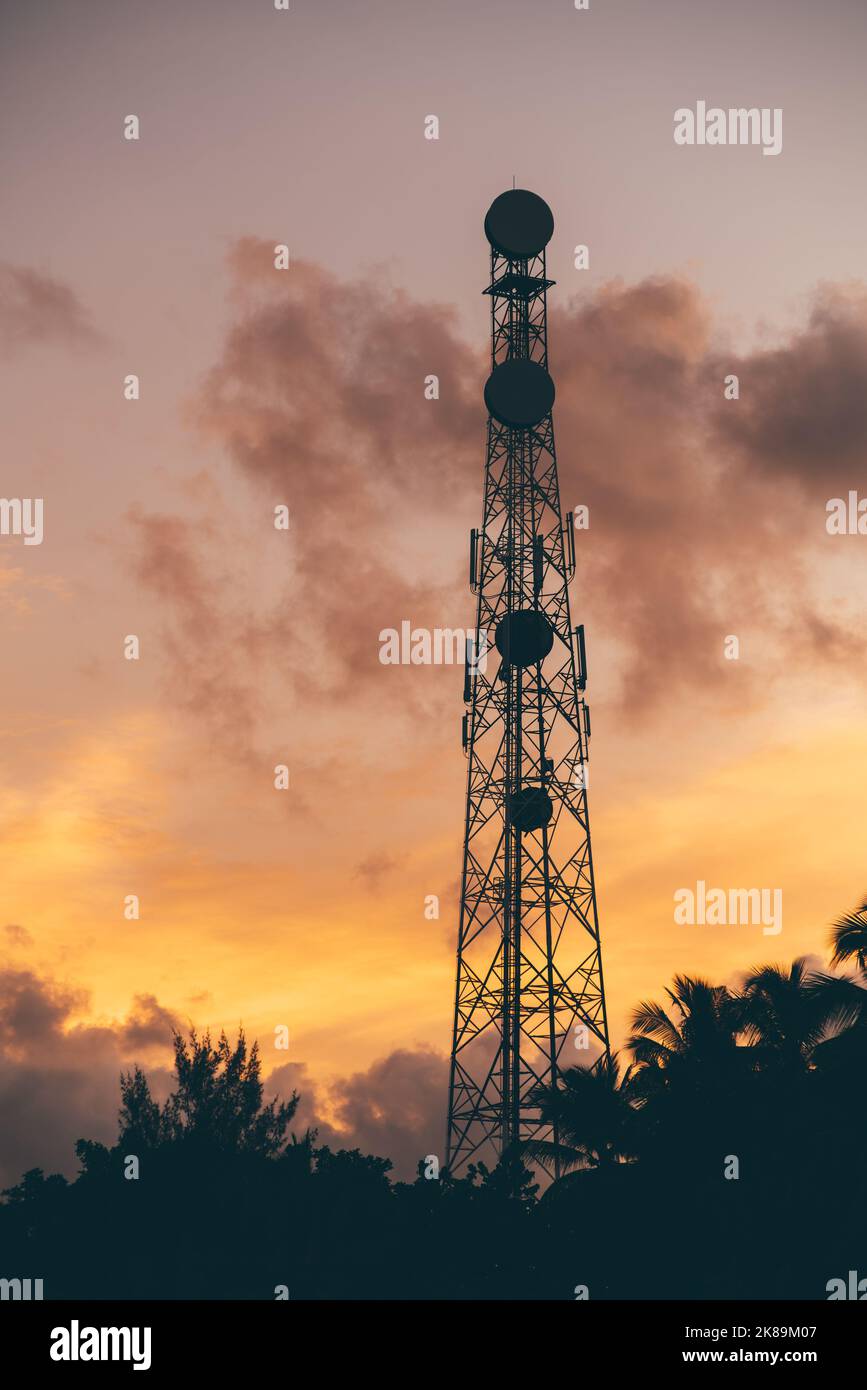 Un cliché vertical avec une silhouette d'une immense tour de communication avec plusieurs antennes de téléphone cellulaire et différents relais avec un magnifique skys de soirée Banque D'Images