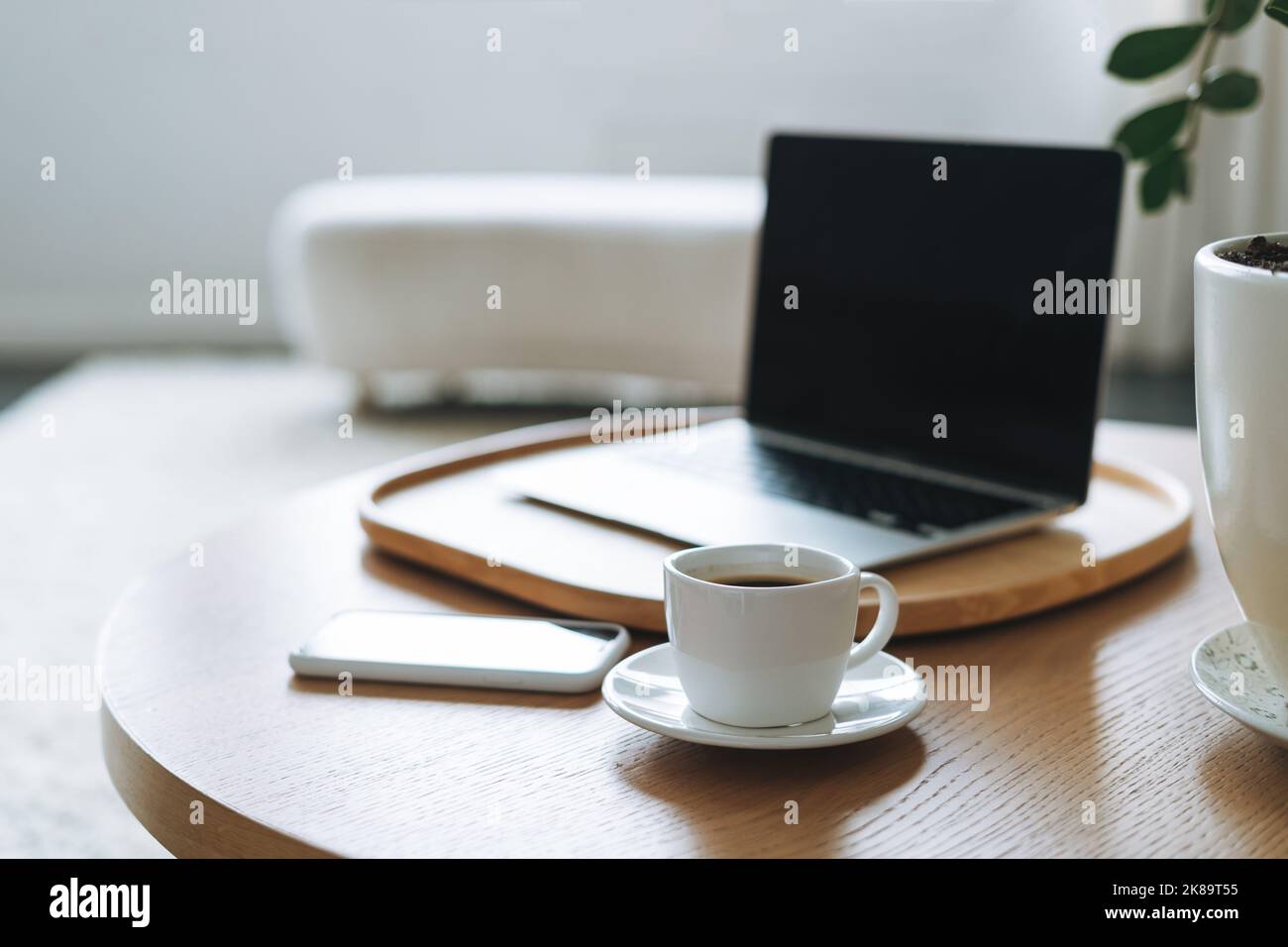 Espace de travail avec une tasse de café, ordinateur portable ouvert sur une table en bois dans la salle de bureau, intérieur d'affaires Banque D'Images