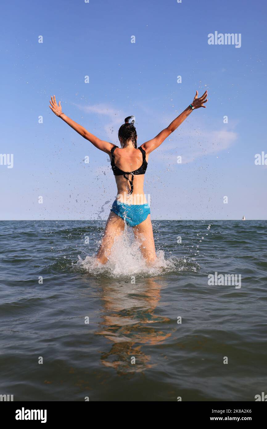 Saut de la fille barbotant hors de la mer se réjouir en été Banque D'Images