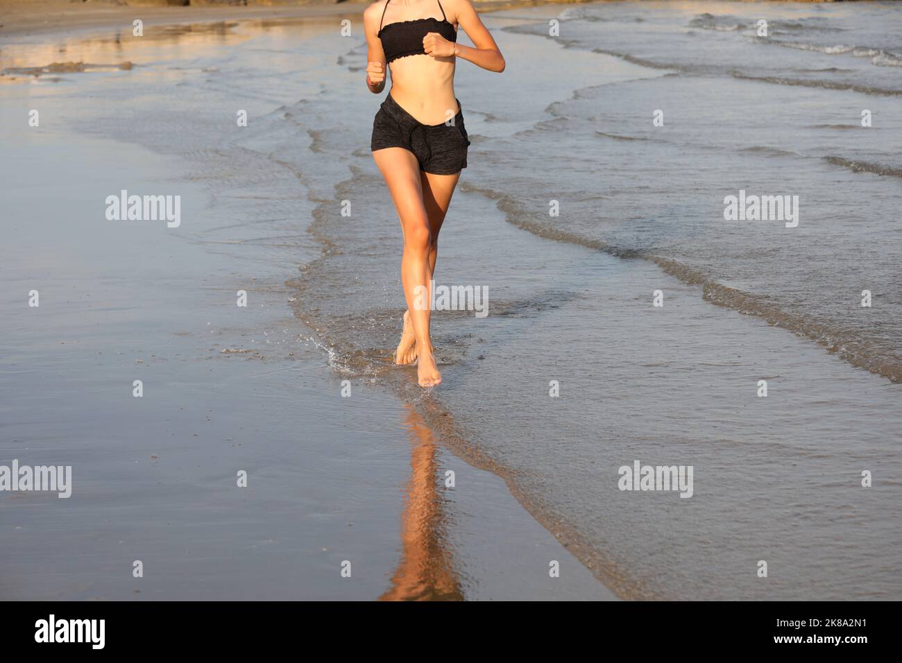 une jeune fille mince court près de la mer en été pour garder la forme Banque D'Images