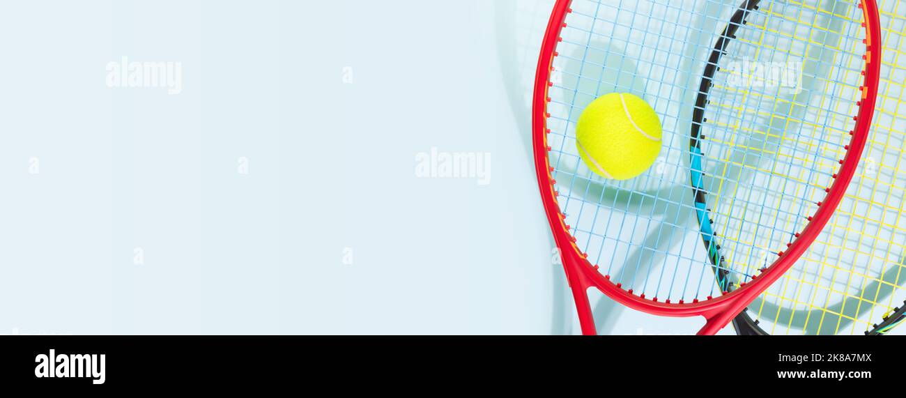 Balle de tennis jaune et raquettes de tennis sur fond bleu Banque D'Images