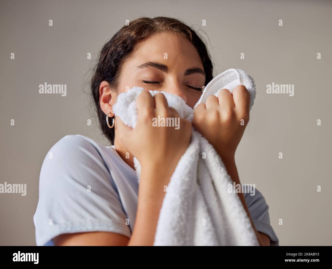 Femme sentant une serviette propre après avoir fait la lessive à sa maison, à l'hôtel ou à la station pendant le nettoyage de printemps. Ménage, femme de ménage ou femme de ménage se lavant pour Banque D'Images