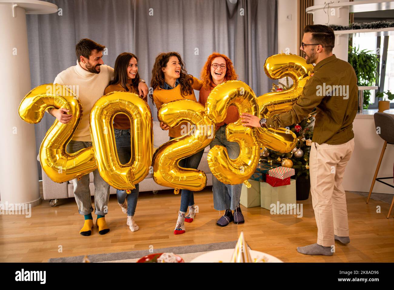 Groupe de jeunes belles personnes dans des vêtements décontractés portant des numéros de couleur or et souriant Banque D'Images