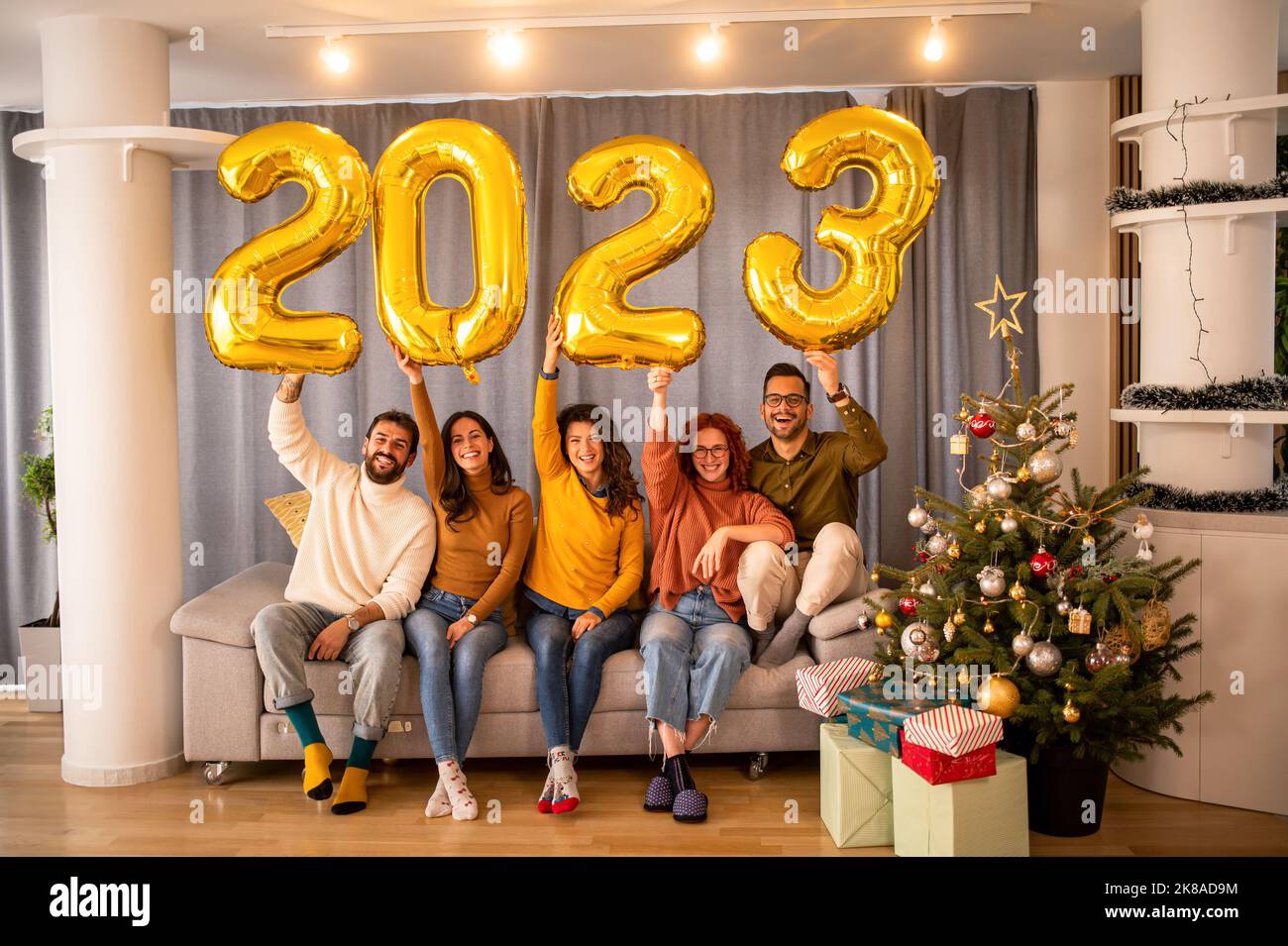 Groupe de jeunes belles personnes dans des vêtements décontractés portant des numéros de couleur or et souriant Banque D'Images