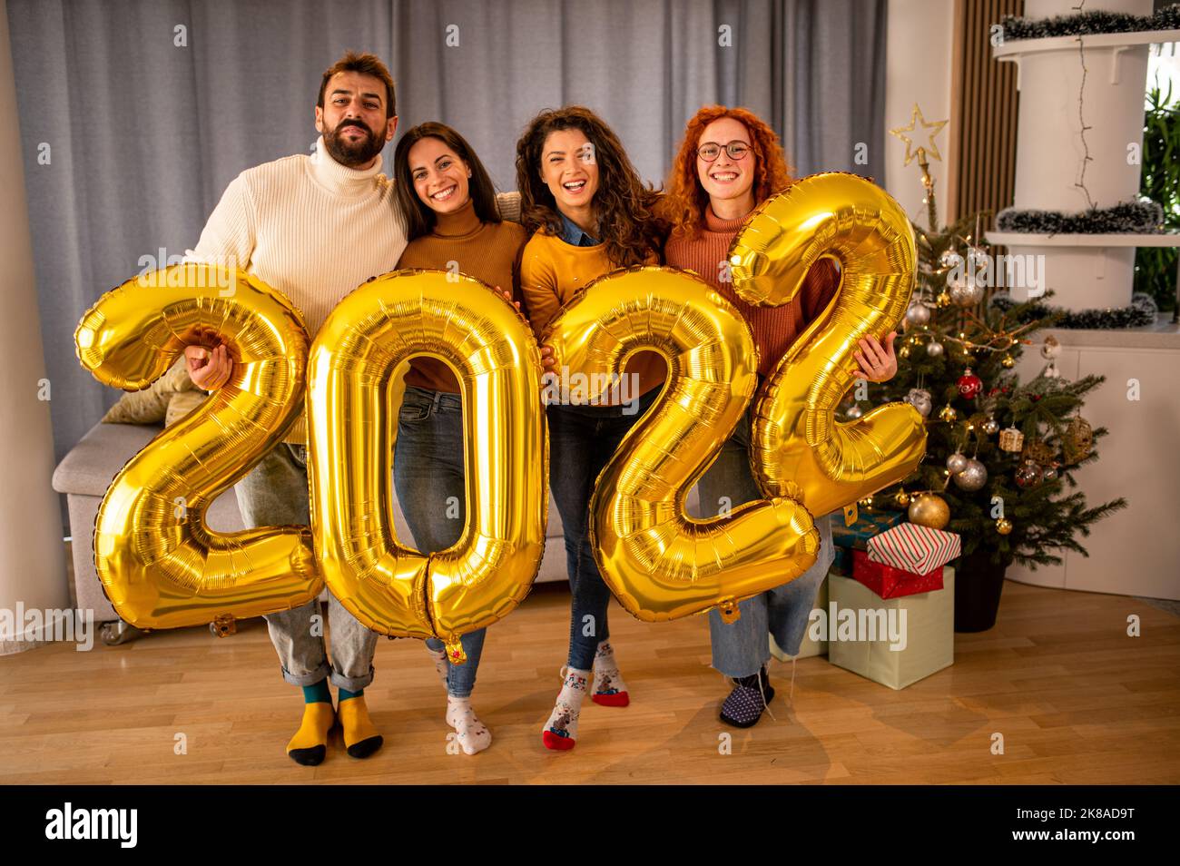 Groupe de jeunes belles personnes dans des vêtements décontractés portant des numéros de couleur or et souriant Banque D'Images