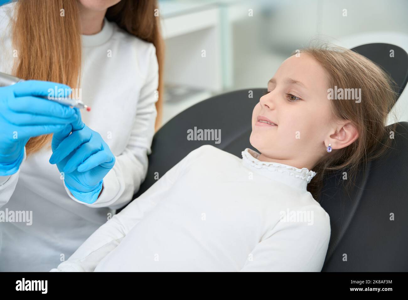 Сhild communiquer avec le dentiste pédiatrique avant la procédure de polissage des dents Banque D'Images
