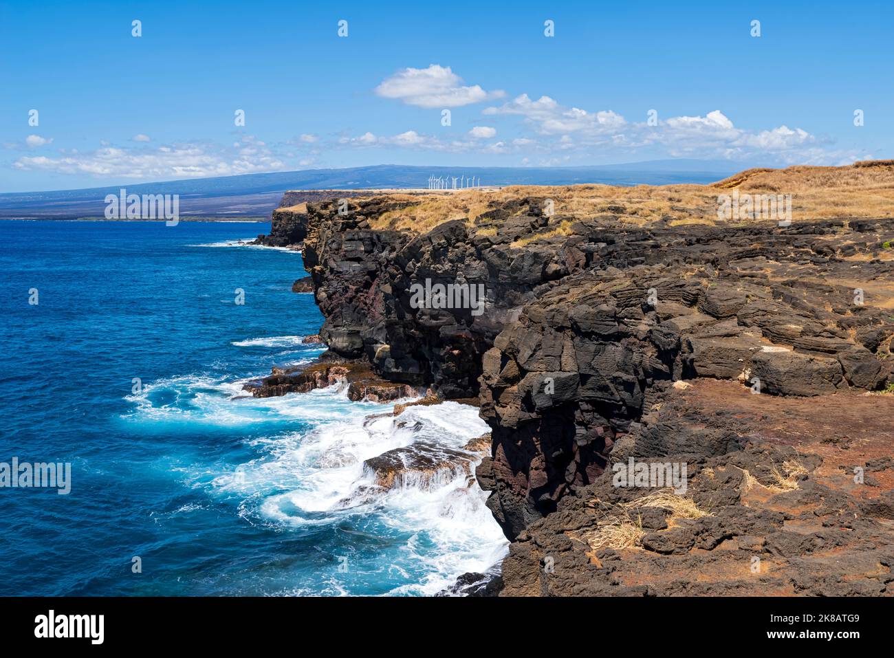 falaises le long de la côte à ka lae ou au point sud d'hawaï point le plus au sud des états-unis et éoliennes à distance Banque D'Images