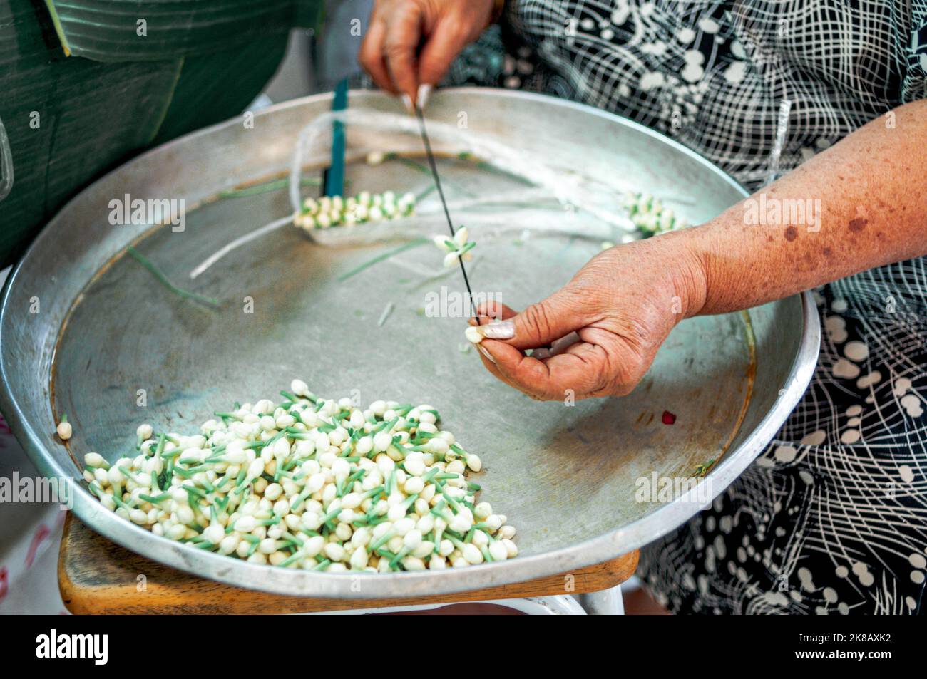 Fermez les mains du vendeur de rue en faisant un collier jasmin Banque D'Images