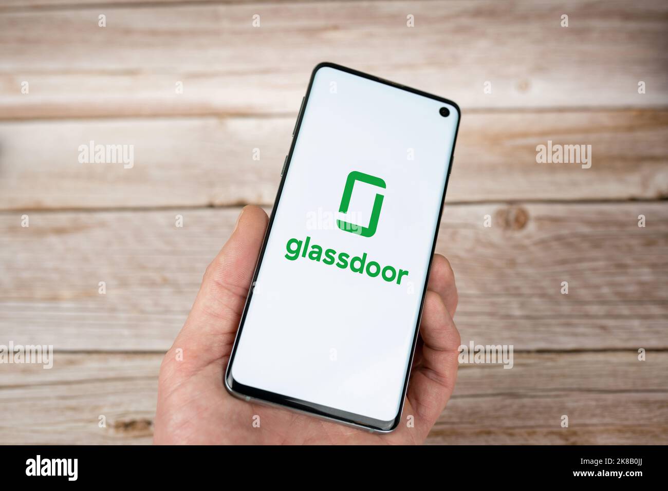 Logo Glassdoor sur l'écran d'un smartphone en main, fond en bois. Application et site Web pour la recherche d'emploi. Swansea, Royaume-Uni - 21 octobre 2022. Banque D'Images