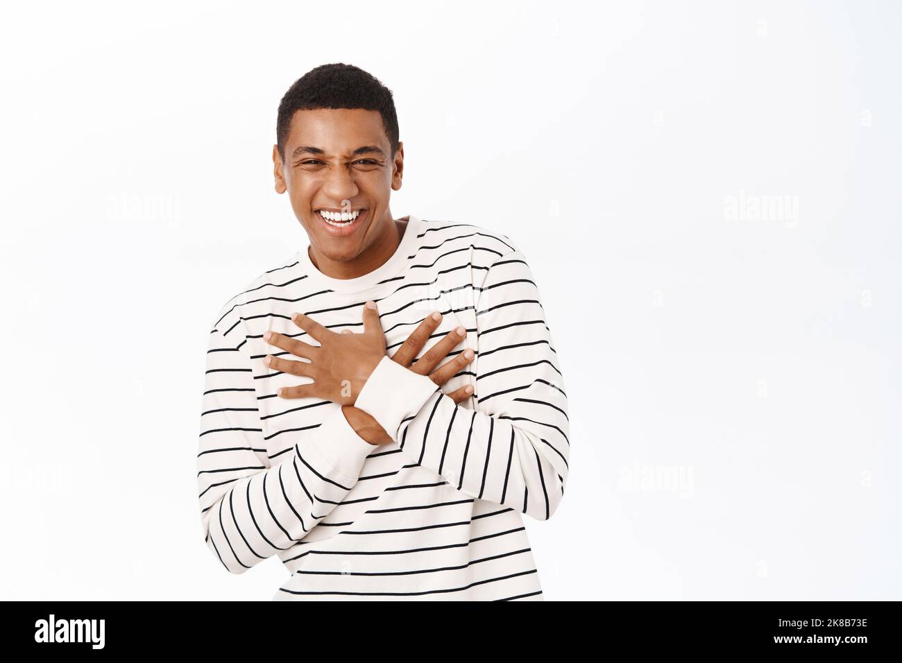 Portrait d'un homme afro-américain riant et souriant, regardant avec joie, debout dans un pull-over rayé sur fond blanc Banque D'Images