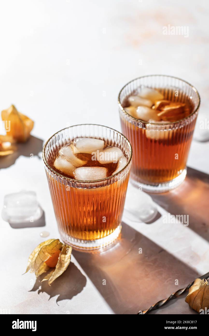 Cocktails de boisson froide saine orange décorés de baies physalis sur fond de marbre avec espace de texte. Buvez photo avec lumière dure et clair shado Banque D'Images