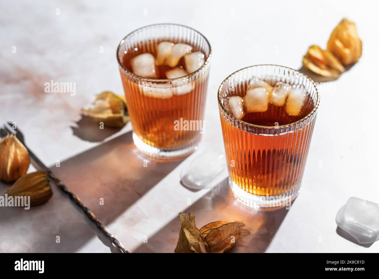 Cocktails de boisson froide saine orange décorés de baies physalis sur fond de marbre. Buvez une photo avec une lumière dure et des ombres claires. Fête d'automne Banque D'Images