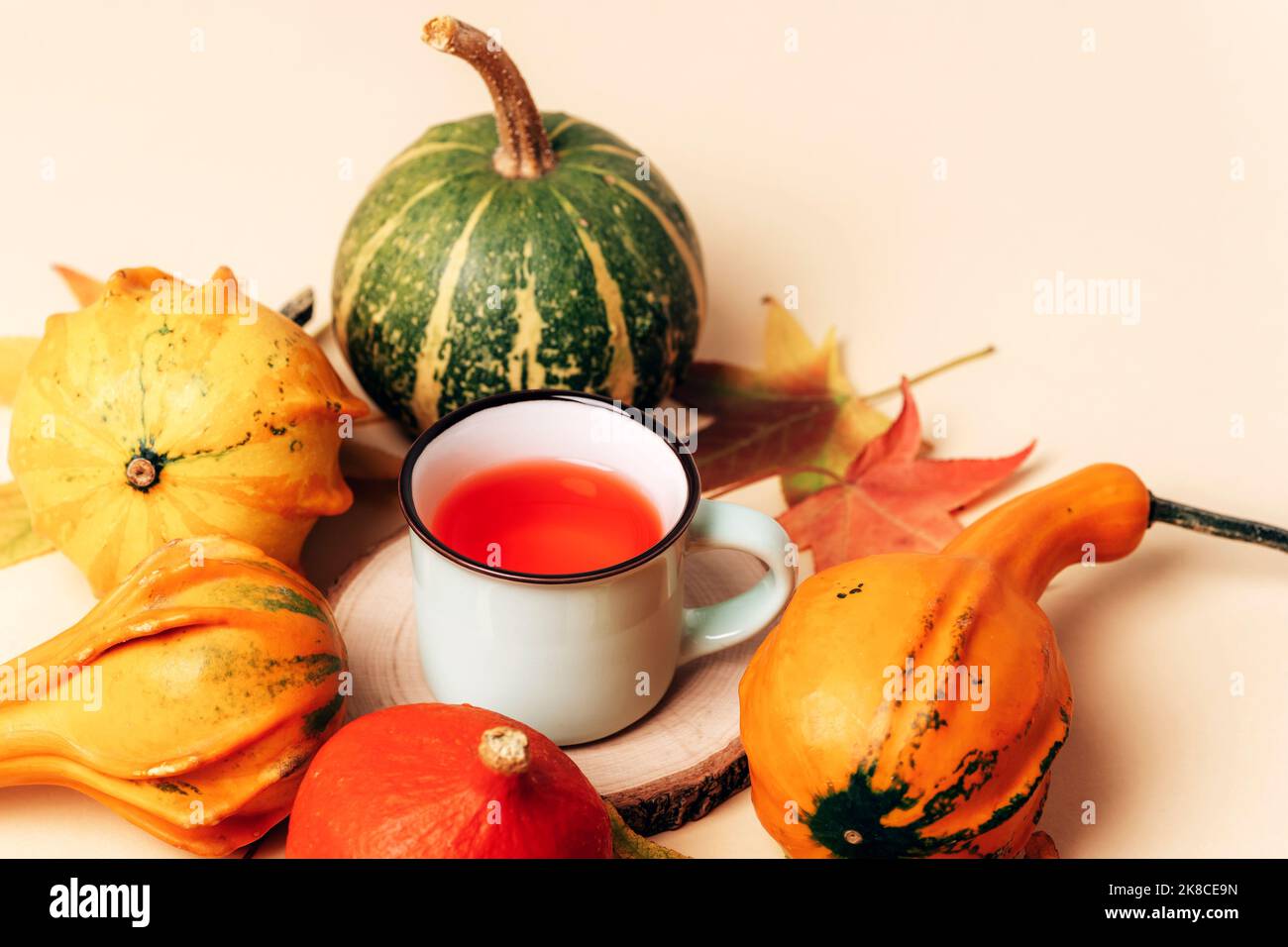 Tasse de thé, citrouilles orange et feuilles d'automne sur table beige. Thanksgiving, concept d'automne. Vue de dessus Banque D'Images