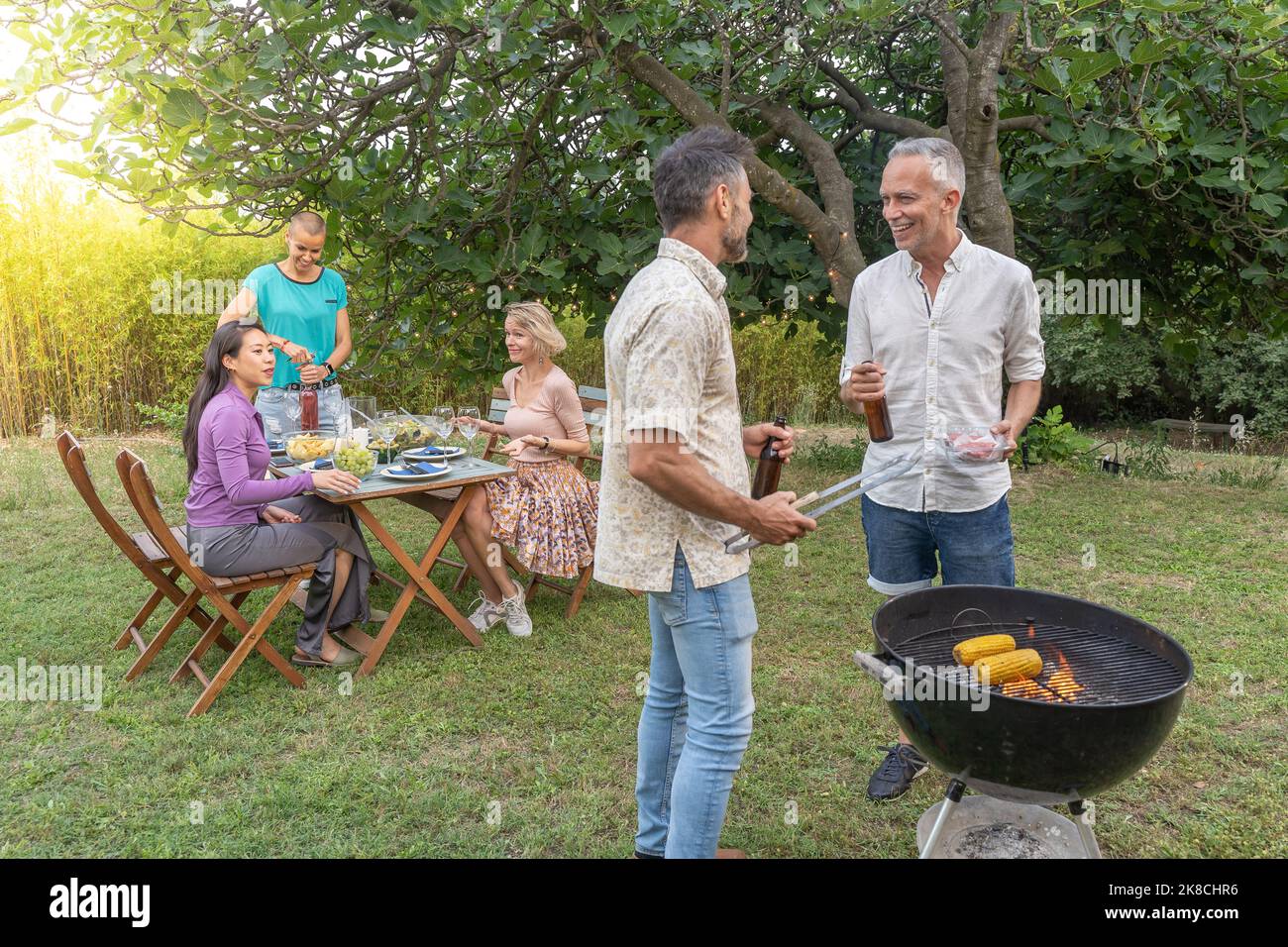 Des amis autour du barbecue souriant heureux et riant ensemble dans le patio restaurant. Banque D'Images