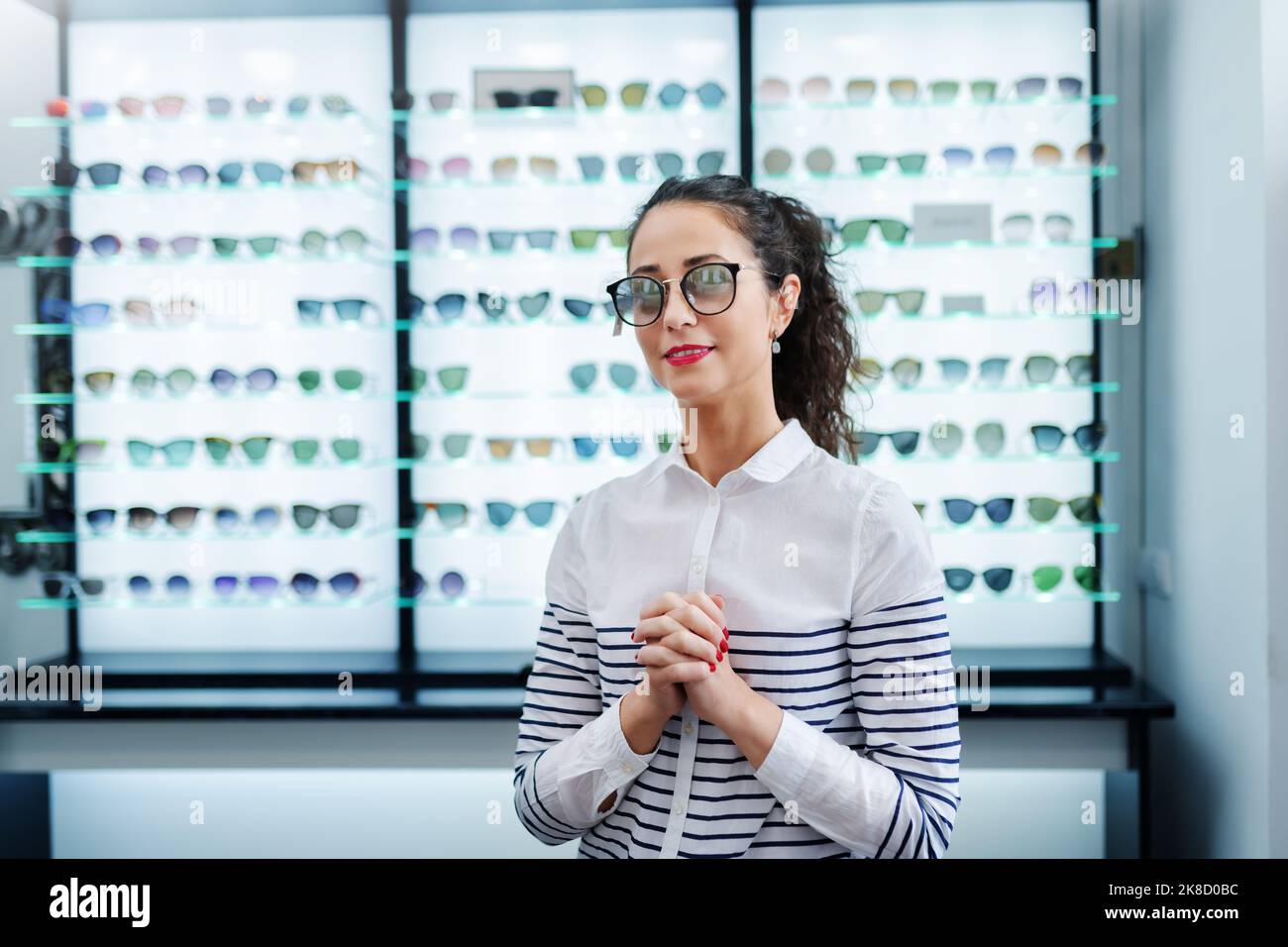Portrait d'une jeune femme en train d'essayer de nouvelles lunettes photogrises dans un magasin d'opticien. Banque D'Images