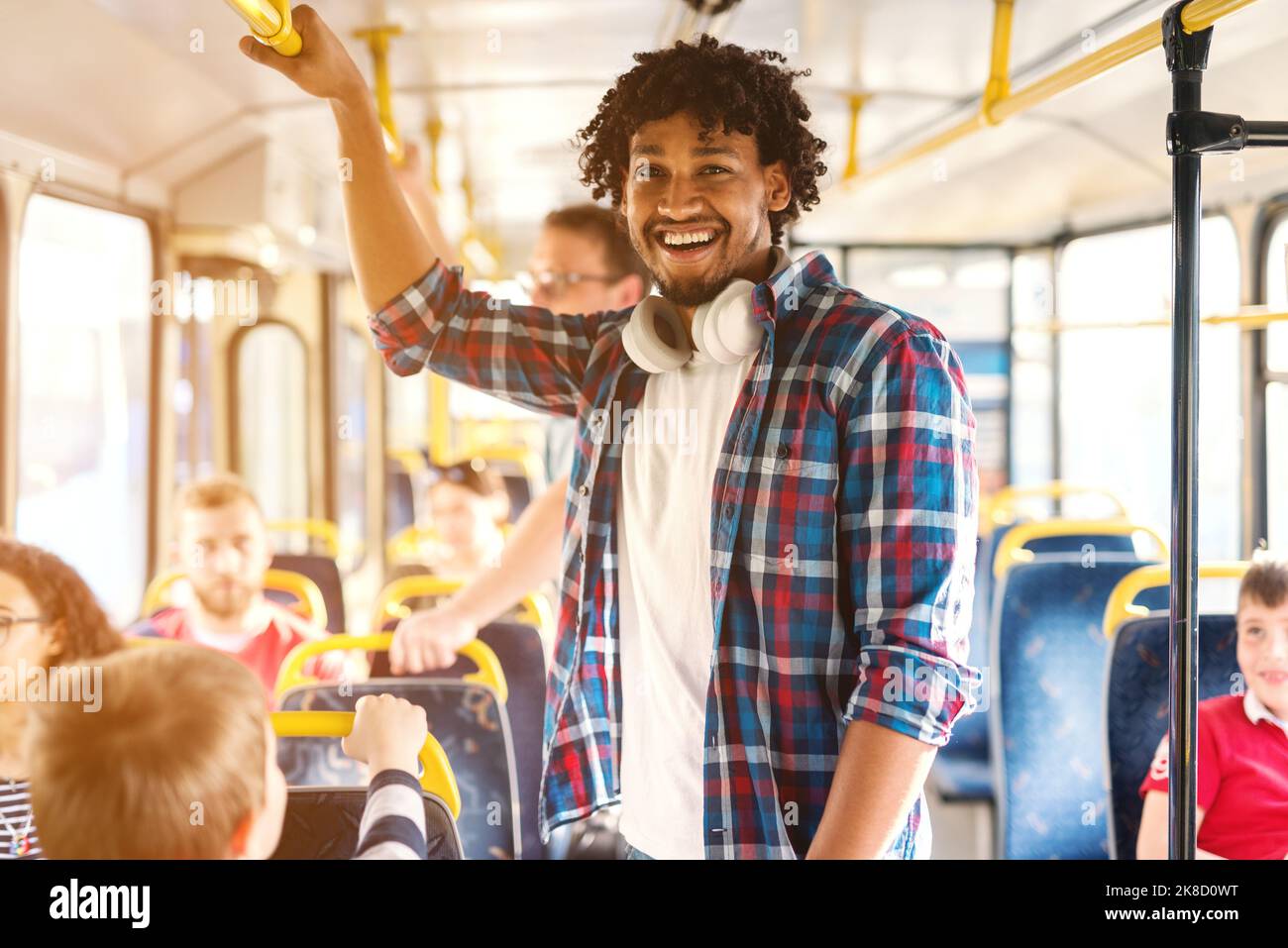 Jeune homme afro-américain souriant à cheval dans le bus de la ville et regardant la caméra. Banque D'Images