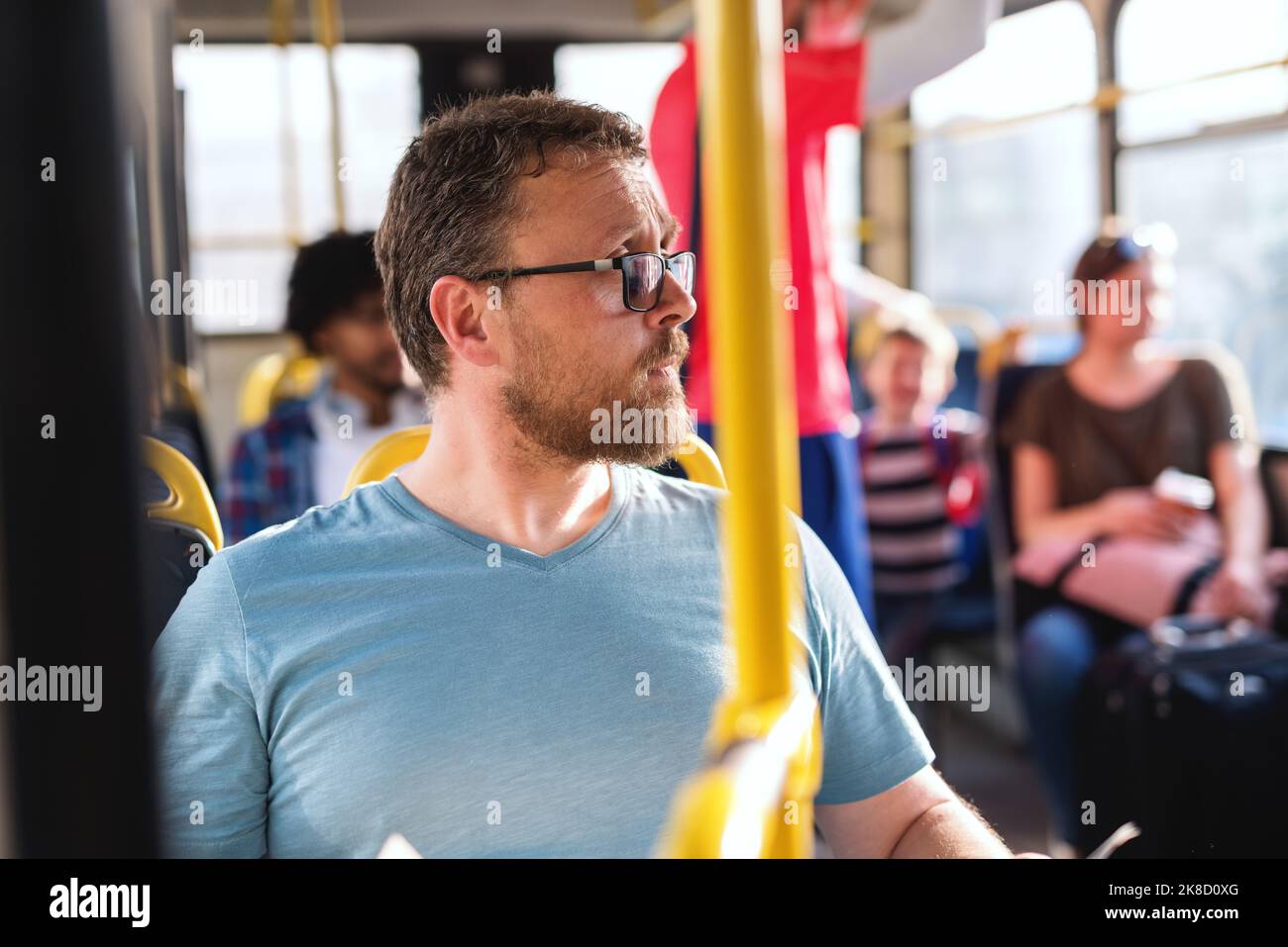 Gros plan de l'homme caucasien avec des lunettes de vue en regardant loin tout en étant assis dans le bus de ville. Banque D'Images