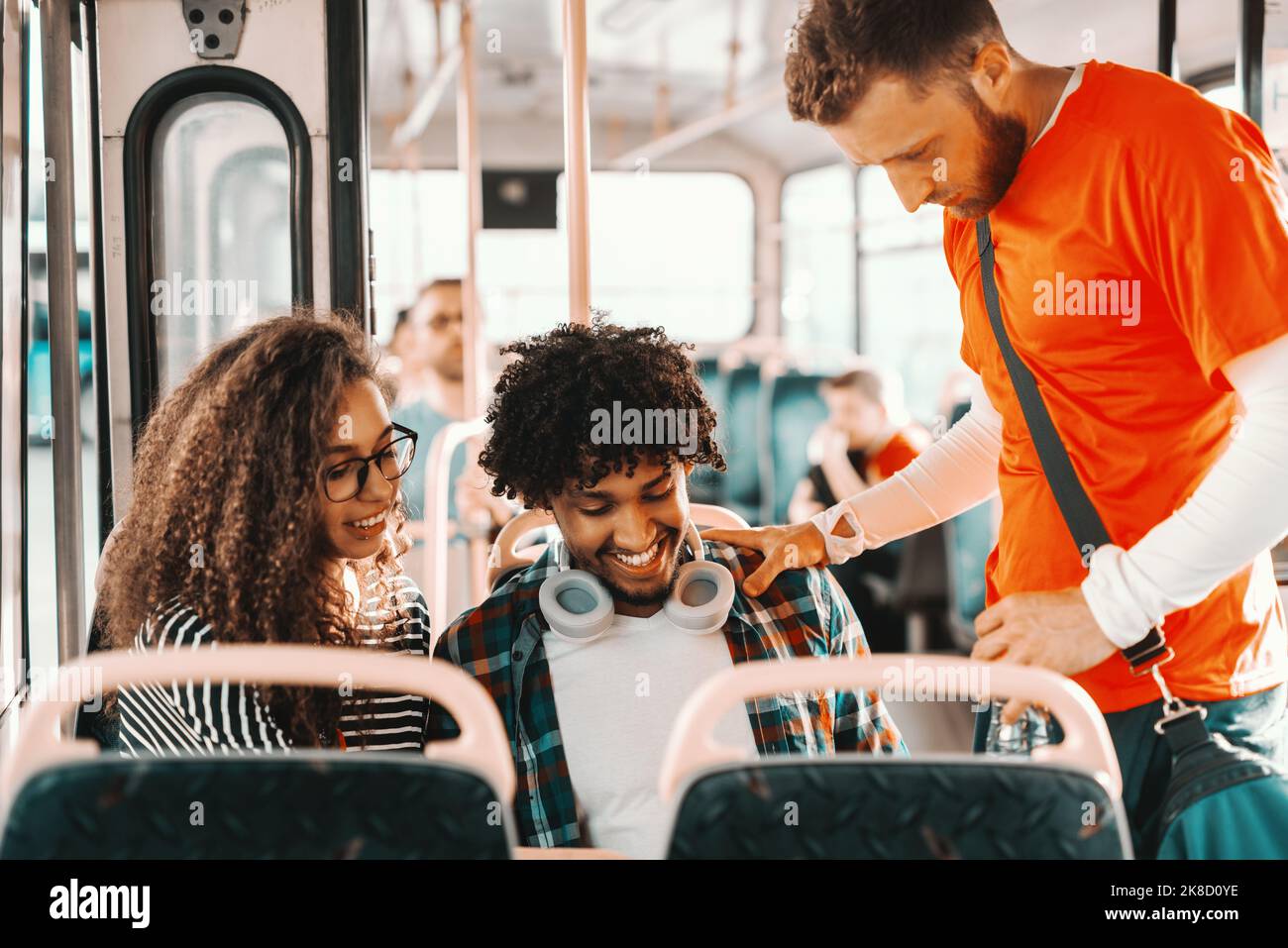 Petit groupe d'amis multiculturels regardant une tablette tout en conduisant dans le bus de ville. Banque D'Images
