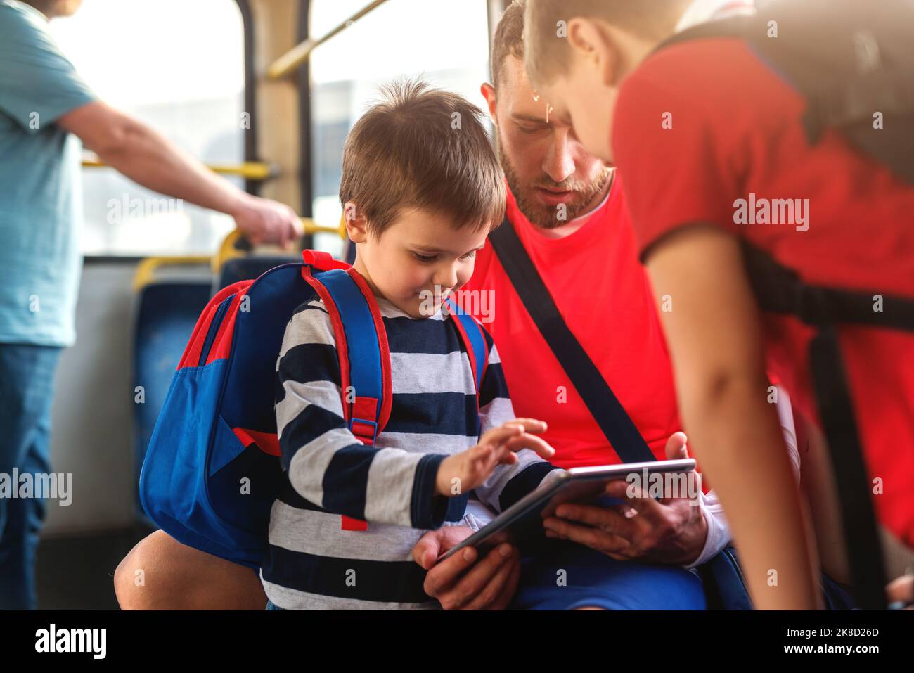 Père et ses deux fils dans les transports en commun jouant avec une tablette. Banque D'Images