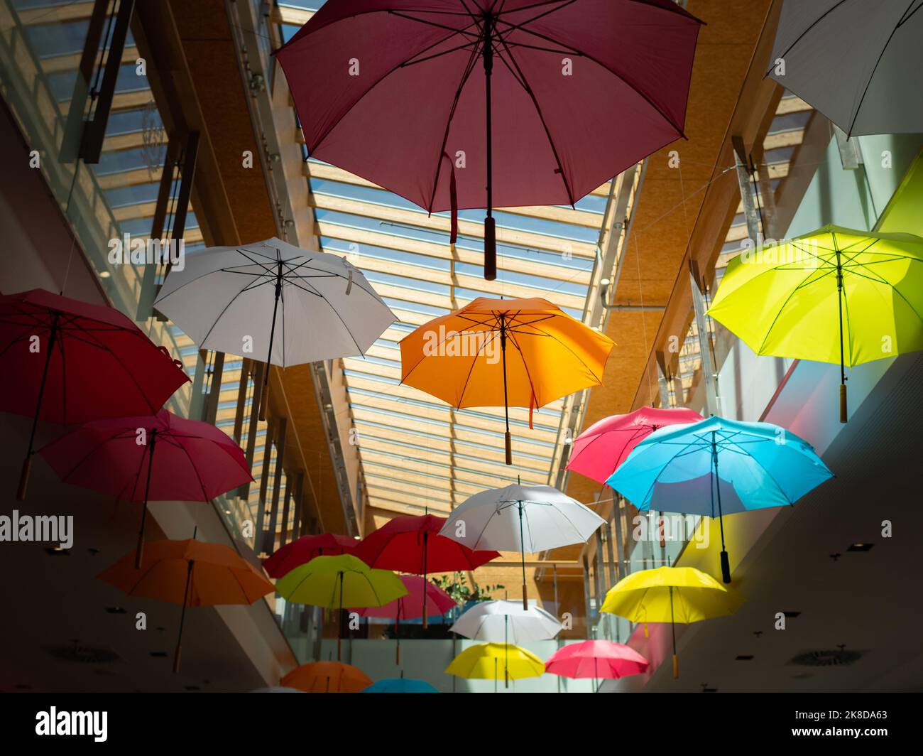 Parasols colorés comme décoration dans un centre commercial. Vue sur le plafond dans le bâtiment. Des parasols ouverts volent autour. Motif de brome. Banque D'Images