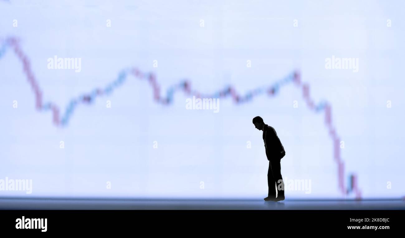 Figurines miniatures silhouette - ralentissement économique ou concept de récession avec le graphique vers le bas dans l'arrière-plan. Banque D'Images