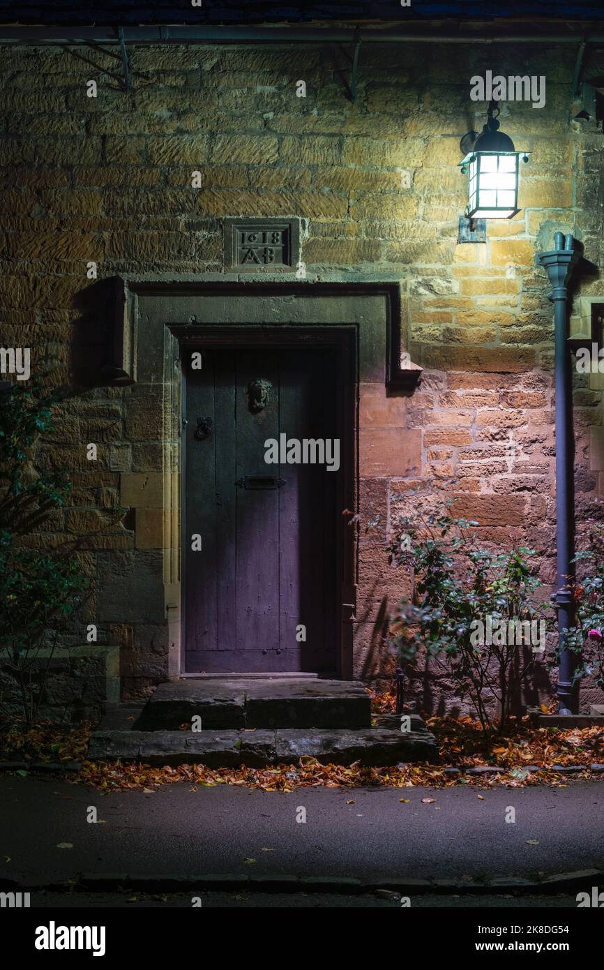 Stanton ancien manoir maison de ferme porte en bois et lampe la nuit. Stanton, Cotswolds, Worcestershire, Angleterre Banque D'Images