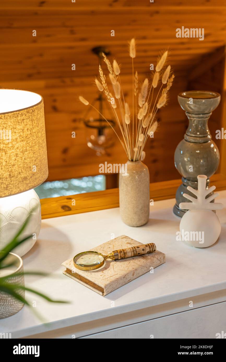 Concept de décoration d'intérieur. Vases divers avec blé sec, une lampe jaune sur une commode blanche dans un intérieur de pièce en bois. Banque D'Images