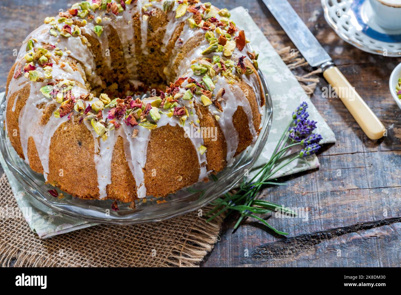 Gâteau parfumé d'amour perse décoré avec du glaçage à la vanille, des pistaches écrasées et des pétales de rose séchés Banque D'Images