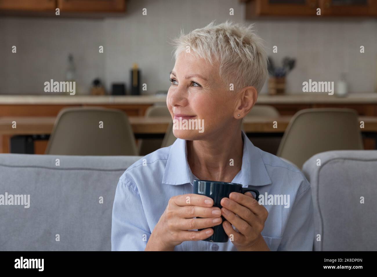 Une femme heureuse et âgée se détendant sur un canapé avec une tasse Banque D'Images