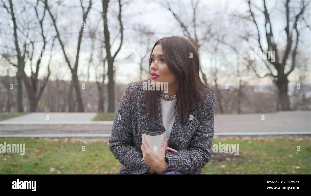 Portrait d'une jeune femme sur un fond de parc d'automne. Un jeune brunette dans un manteau gèle dans la rue. Banque D'Images