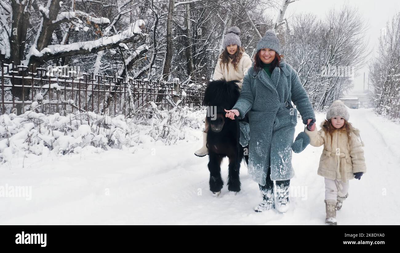 promenade à cheval en hiver. équitation en hiver. balade à cheval en famille le jour d'hiver enneigé. Bonne cutie, petite fille est à cheval sur un poney. Hiver activité familiale à l'extérieur. Photo de haute qualité Banque D'Images