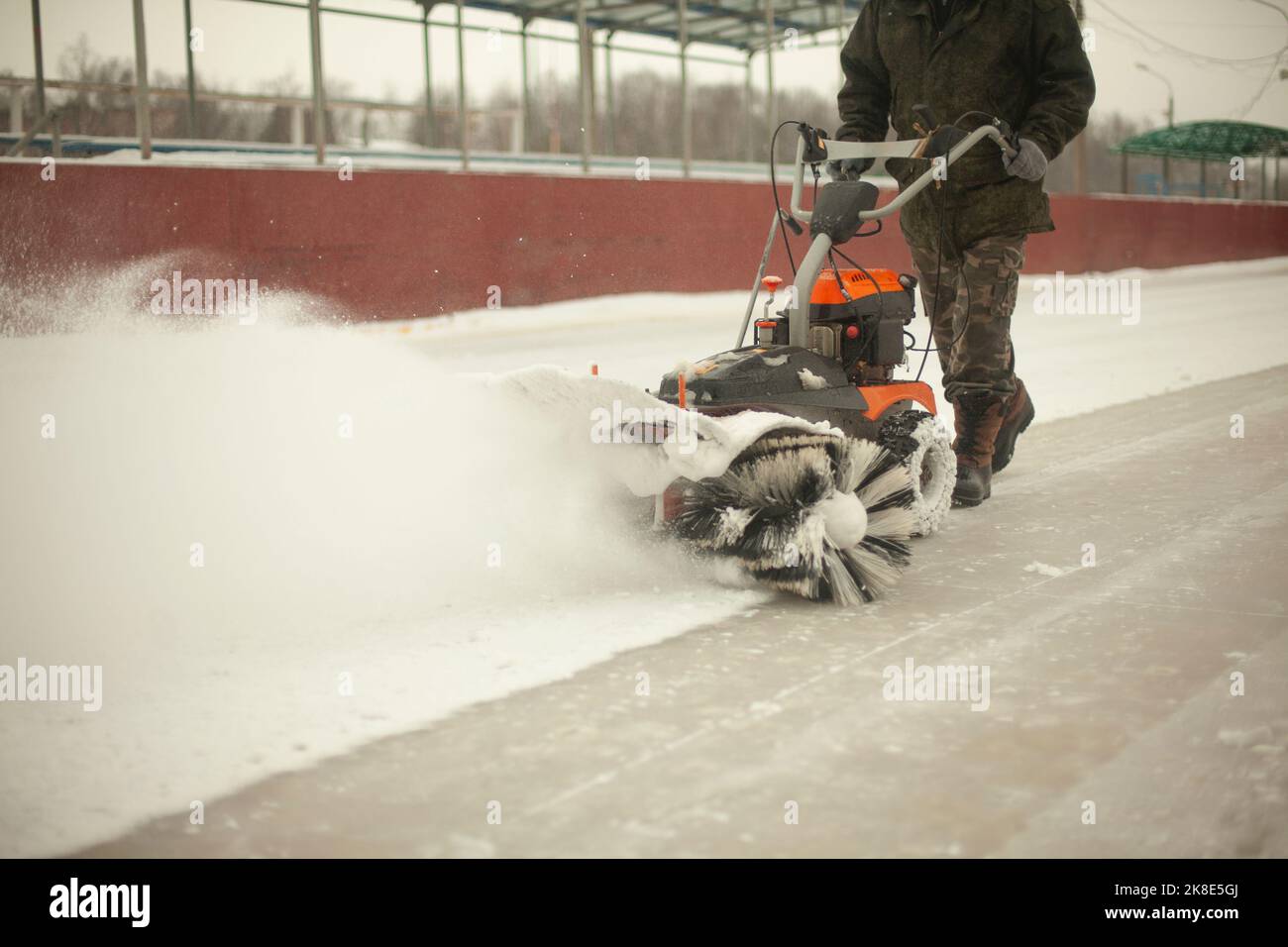 Déneigement à la patinoire. Retrait de la couche de neige de la glace. L'employé nettoie le stade des précipitations. La voiture est le meulage de neige. Banque D'Images