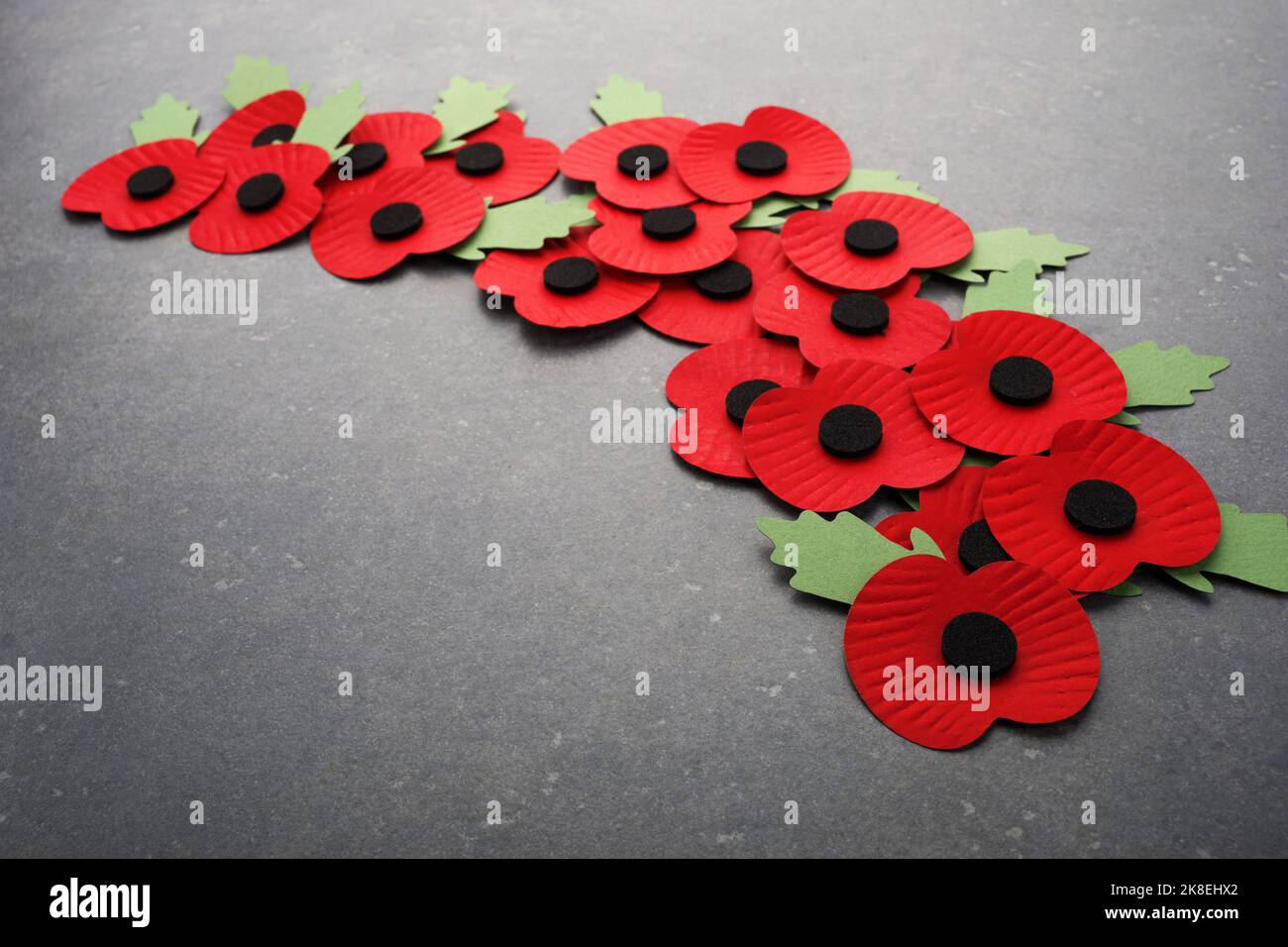 Journée du souvenir de la Guerre mondiale. Des coquelicots en papier rouge sur fond de pierre sombre Banque D'Images