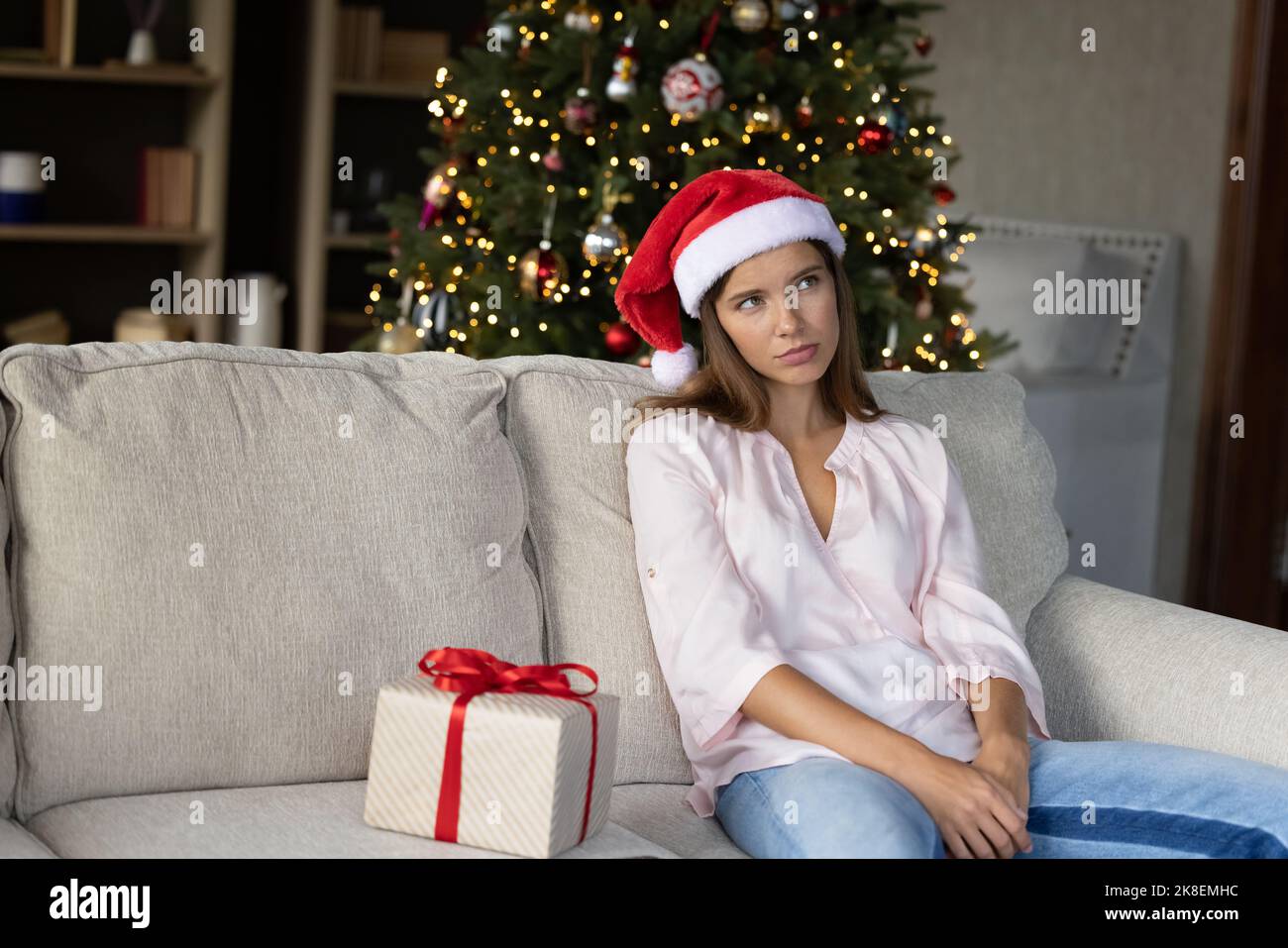 Jeune femme malheureuse célébrant Noël seul à la maison. Banque D'Images