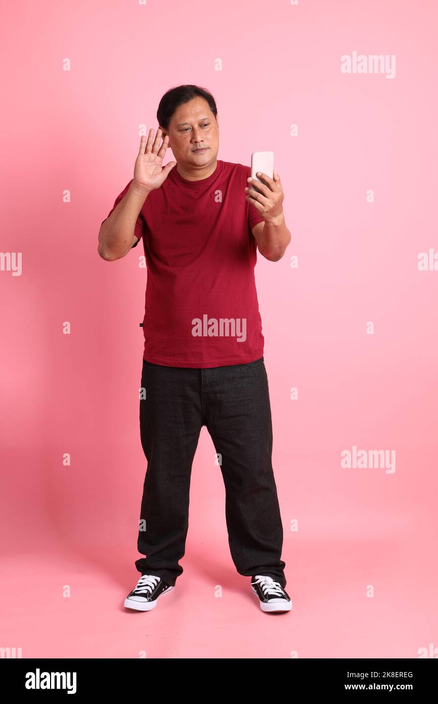 L'homme asiatique de 40s adultes en surpoids se tenant sur fond rose. Banque D'Images