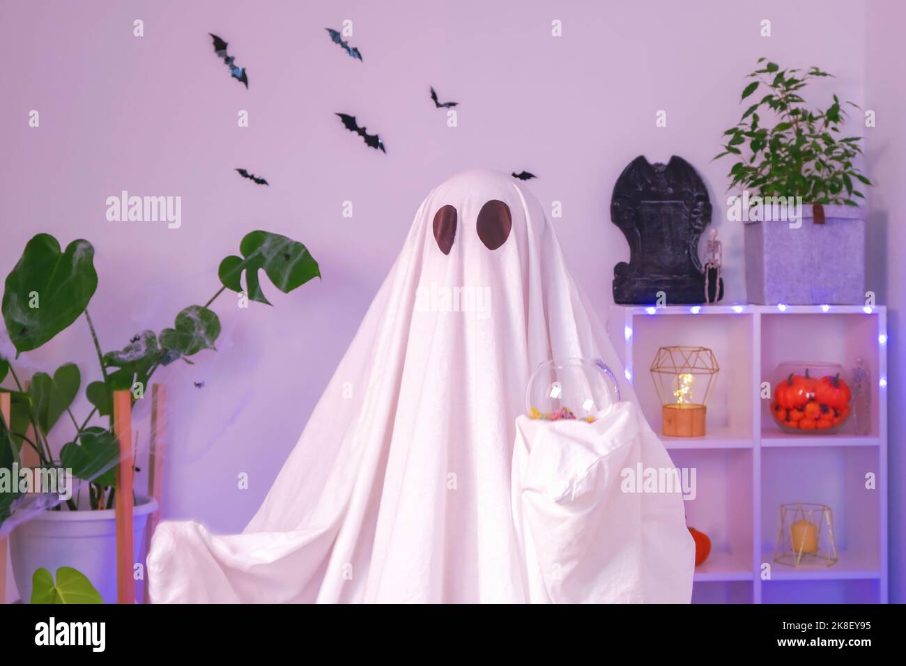 Un fantôme mange des bonbons pour Halloween. Un fantôme mange des vers, des bonbons, des bonbons ou du baiser, des trucs ou des gâteries. Joyeux Halloween. Néon. Banque D'Images