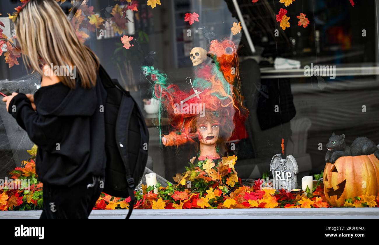 Brighton UK 23rd octobre 2022 - Un visiteur passe par une fenêtre décorée pour Halloween dans un salon de coiffure un jour exceptionnellement chaud pour la période de l'année à Brighton aujourd'hui que les températures devraient atteindre 20 degrés dans certaines parties du Sud-est . : Crédit Simon Dack / Alamy Live News Banque D'Images