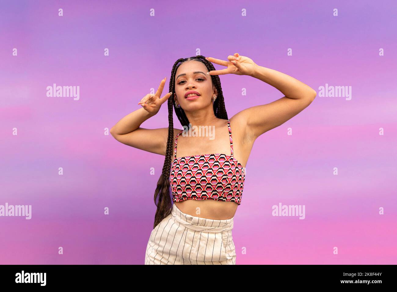 Femme signe de paix devant le mur violet Banque D'Images