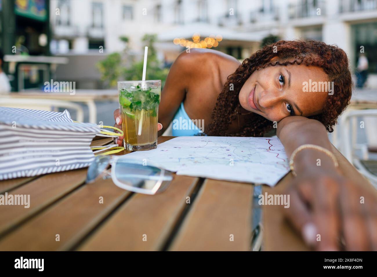 Femme souriante se penchée la tête sur le bras à la table Banque D'Images