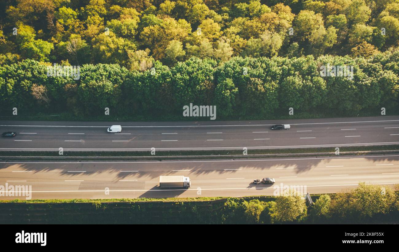 Véhicules sur l'autoroute par des arbres verts Banque D'Images