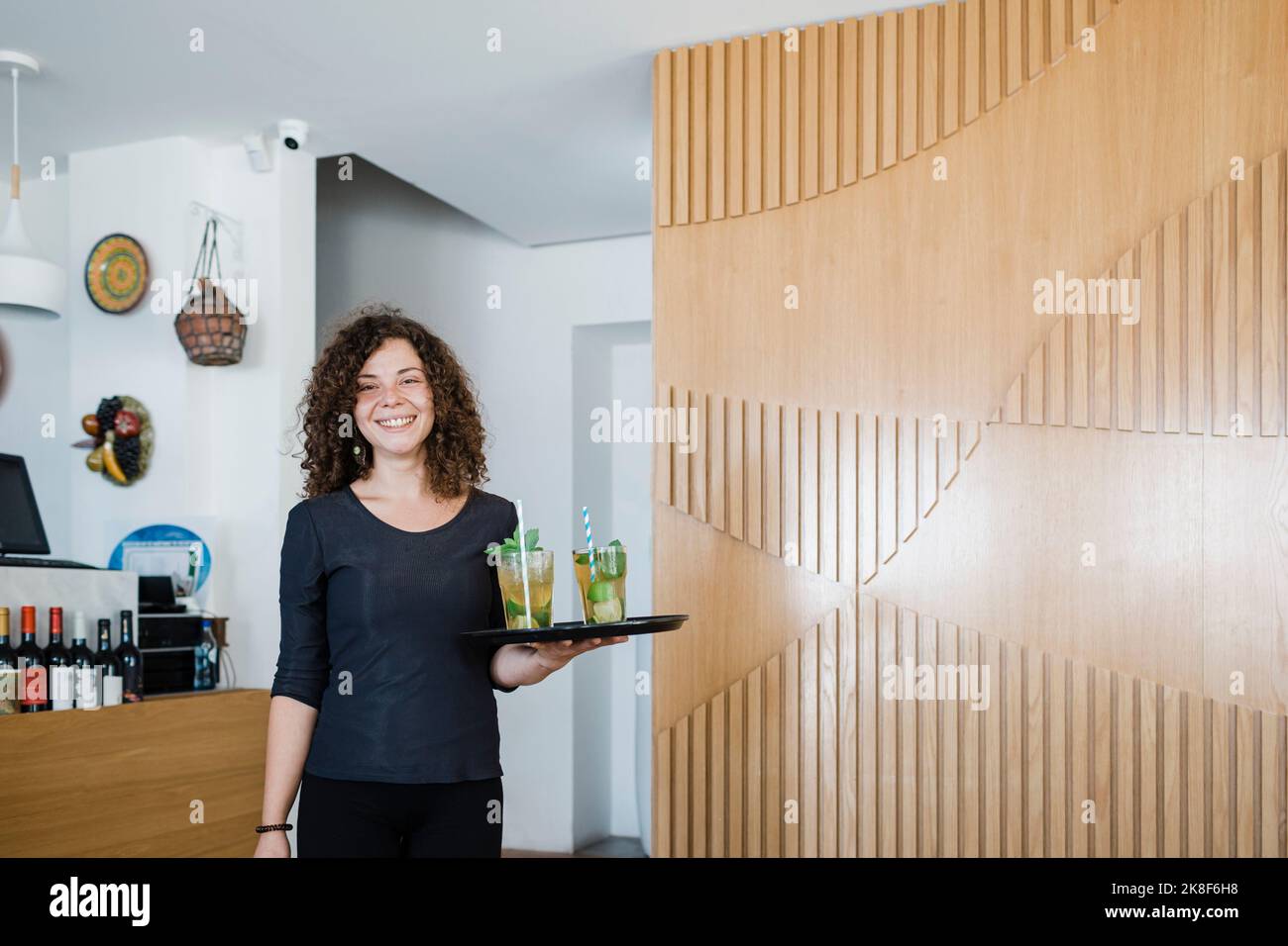Bonne serveuse jeune avec plateau servant des boissons au restaurant Banque D'Images