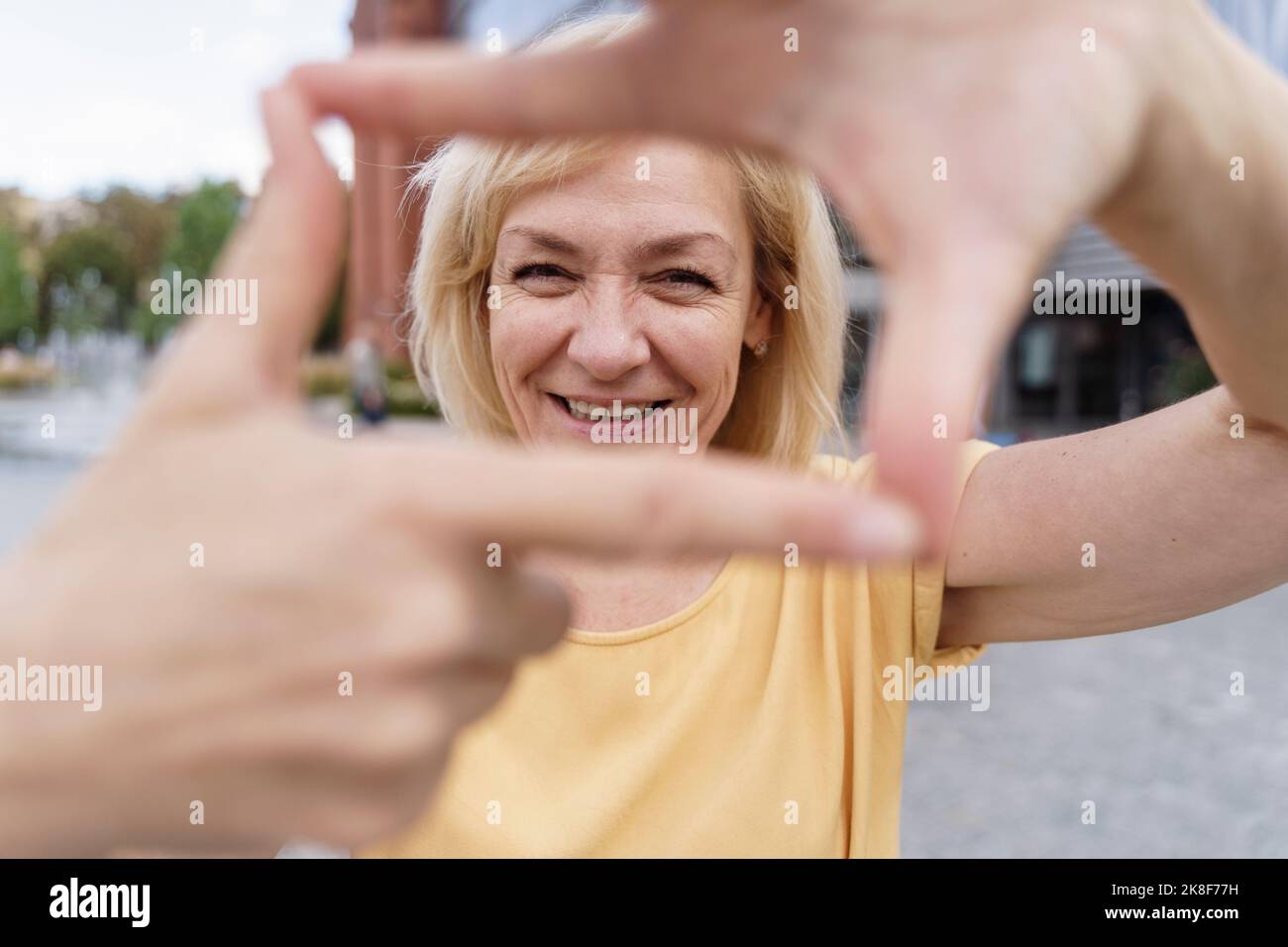 Bonne femme mûre faisant le cadre de doigt Banque D'Images