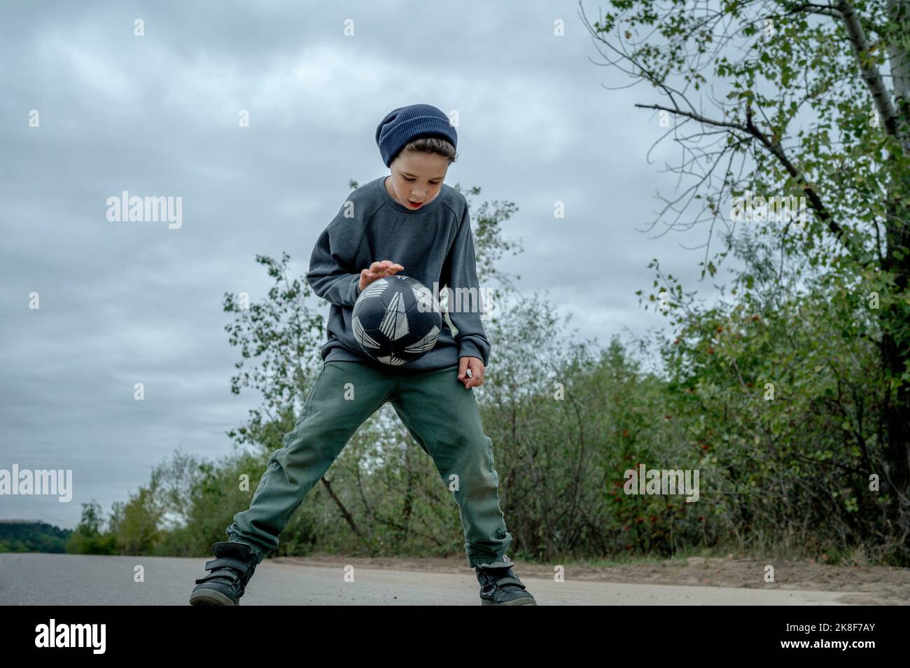 Garçon portant un chapeau en tricot dribbling basket ballon sur la marche Banque D'Images